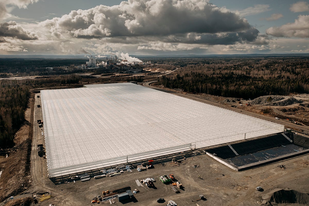 An expansive industrial facility, possibly a warehouse or a distribution center, in the midst of construction. The large white structure is the main focus, with its flat roof and multiple sections visible.